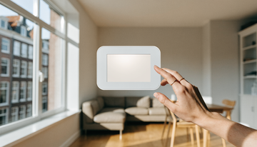 Draadloos alarmpaneel met touchscreen aan de muur in een lichte woonkamer, hand bedient het paneel